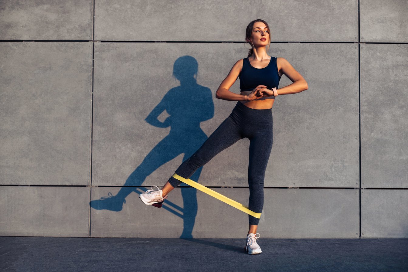 Sporty Woman Doing Exercises with Resistance Band, Fitness Woman Doing Leg Exercises with Yellow Fitness Rubber Band