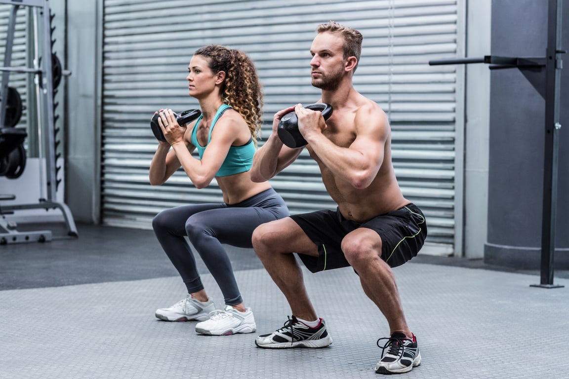 Muscular couple exercising with kettlebells